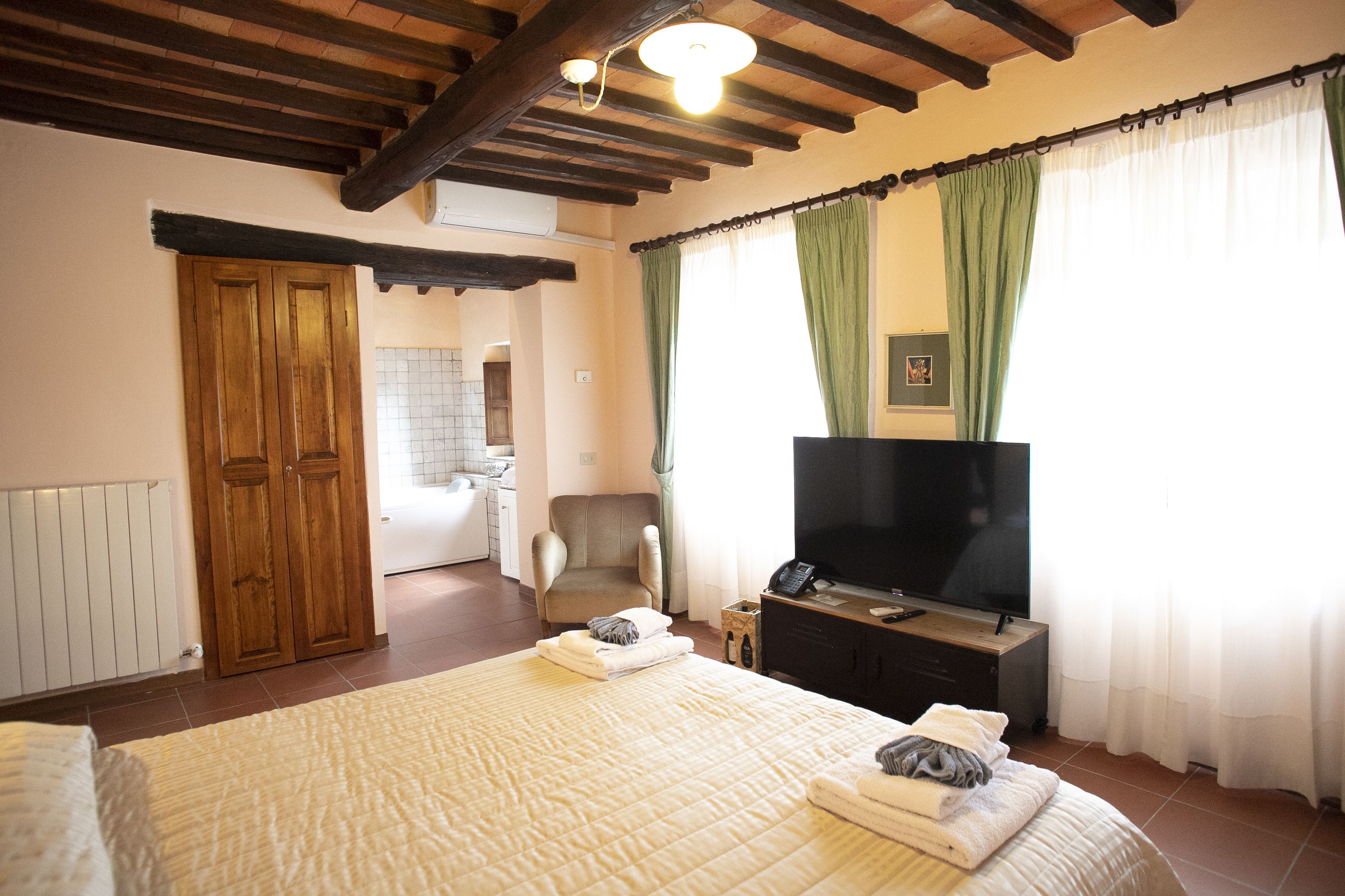 Un dormitorio con una cama, televisión, una silla y un armario de madera.