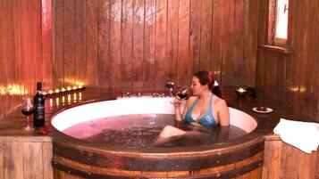 Guests can unwind in a spacious room with a large round bathtub and a window offering a view of the outside.