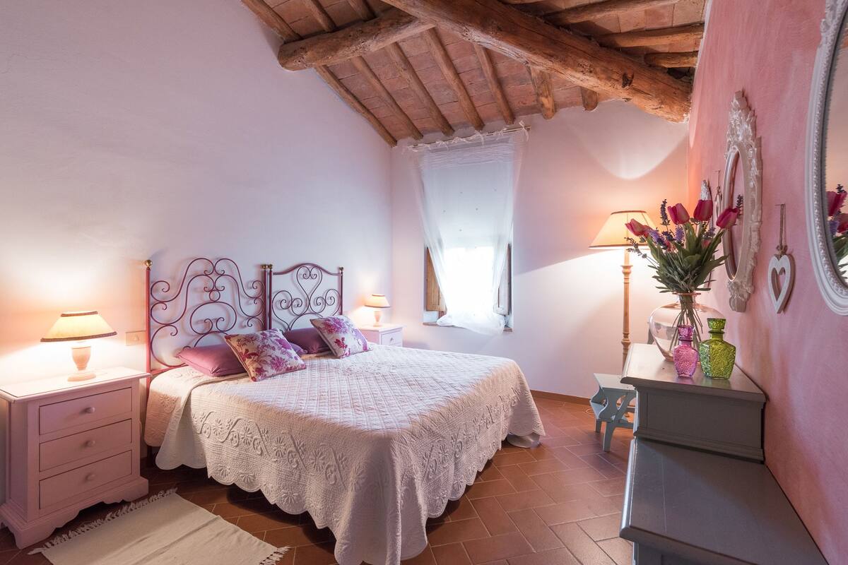 A bedroom with a bed, nightstands, a dresser, a mirror, and a window with curtains.