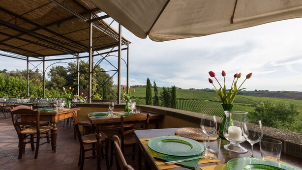 An outdoor dining area with tables set for four, surrounded by a pergola with a view of the countryside. - Podere Torricella (Montespertoli)