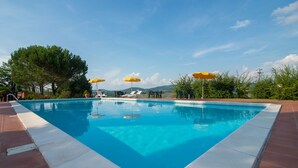 A rectangular swimming pool with clear blue water, surrounded by a tiled deck. - Podere Torricella (Montespertoli)