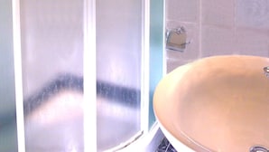 A bathroom with a glass shower enclosure, a sink, and a window above the sink. - Hotel Kriss (Rome)
