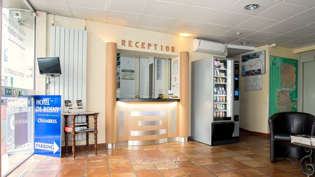 A hotel reception area with a reception desk, a vending machine, a map on the wall, and a sign for the hotel rooms. - Hôtel de Rosny (Tours)