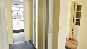A hallway with a glass door leading to a parking area. - Hôtel de Rosny (Tours)