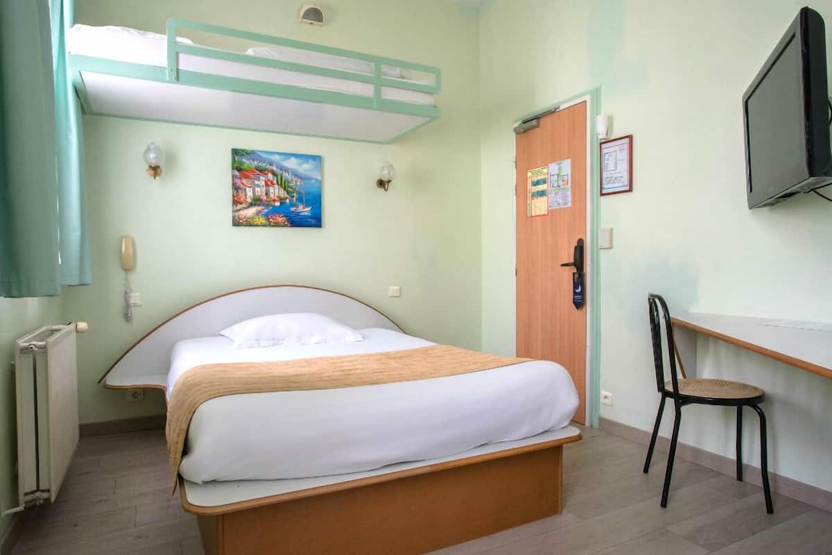 A bedroom with a bunk bed, a desk, a chair, a television, and a painting on the wall.