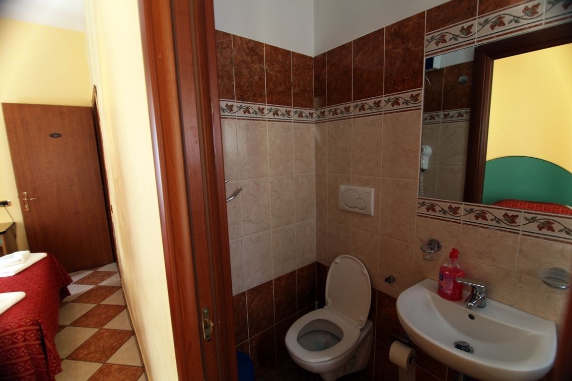 A bathroom with a toilet, sink, and a mirror.