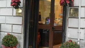 The Hollywood Hotel entrance with a sign above the door, two potted plants on either side, and a doormat in front. - Hollywood Roma (Rome)