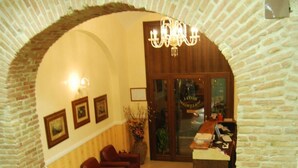 A lobby with a brick archway, a chandelier, leather sofas, a reception desk, and a tiled floor. - Hollywood Roma (Rome)