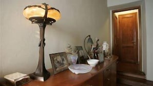 A wooden desk with a lamp, framed pictures, and a door in the background. - Gianna's B&B (Florence)