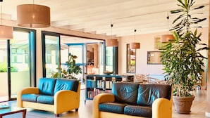 Un hall d’entrée moderne avec des canapés en cuir, une table basse et une grande plante en pot.