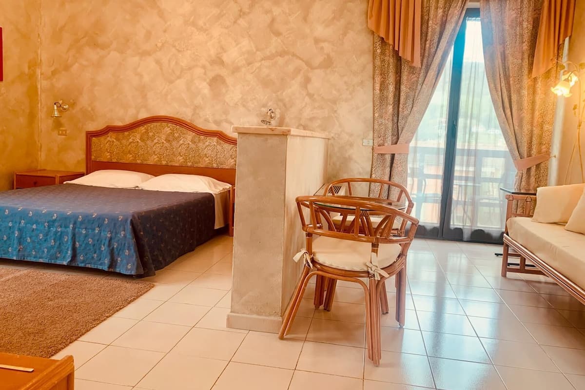 A hotel room with a bed, a desk, a chair, and a sofa.
