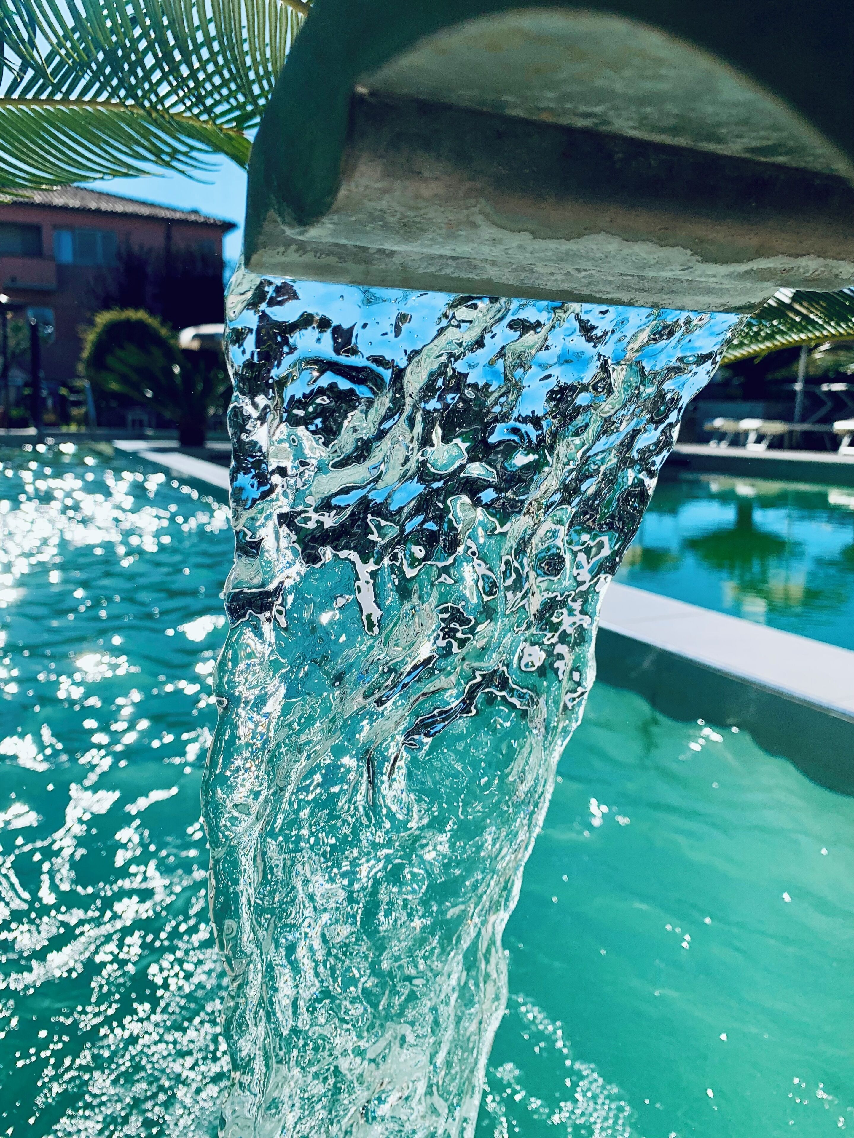 Un élément décoratif aquatique offrant une vue dégagée sur la piscine et les bâtiments environnants.