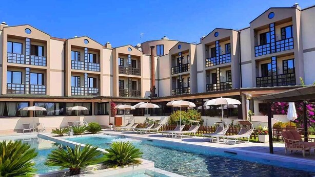 Un hôtel doté de nombreux balcons, d’une piscine et de chaises longues.