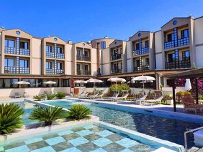 Un hotel con varios balcones, piscina y tumbonas.
