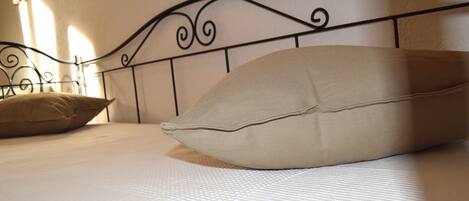 Een opgemaakt bed met hoofdbord, kussens en een gewatteerde sprei.