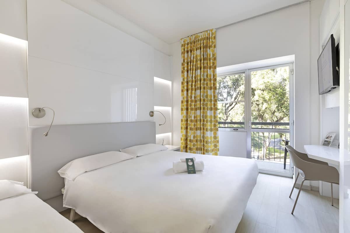 Habitación de hotel con una cama grande, un escritorio y una ventana con cortinas.