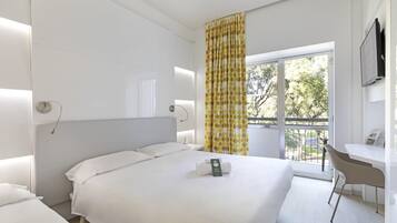 Een hotelkamer met een groot bed, een bureau en een raam met gordijnen.