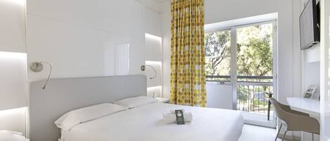 Een hotelkamer met een groot bed, een bureau en een raam met gordijnen.