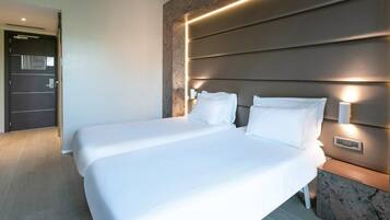 A modern hotel room with a large bed, a marble accent wall, and built-in lighting.