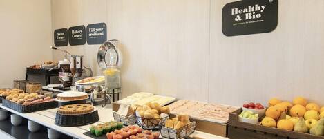 A buffet with various food items including pastries, bread, and fruits.