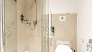 A modern bathroom with a glass-enclosed shower, a toilet, and a sink.
