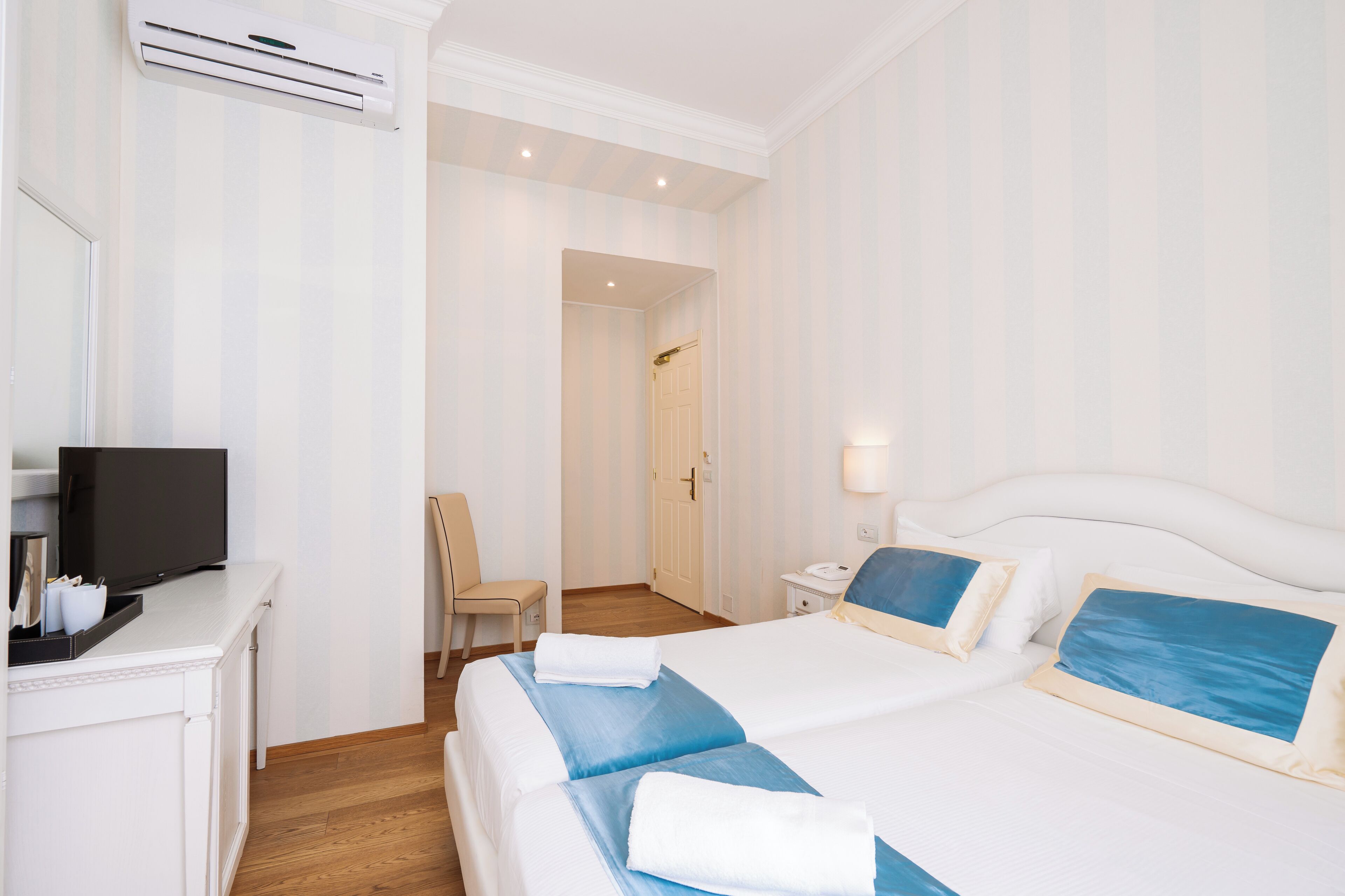 A hotel room with a bed, a TV, a desk, and a chair.