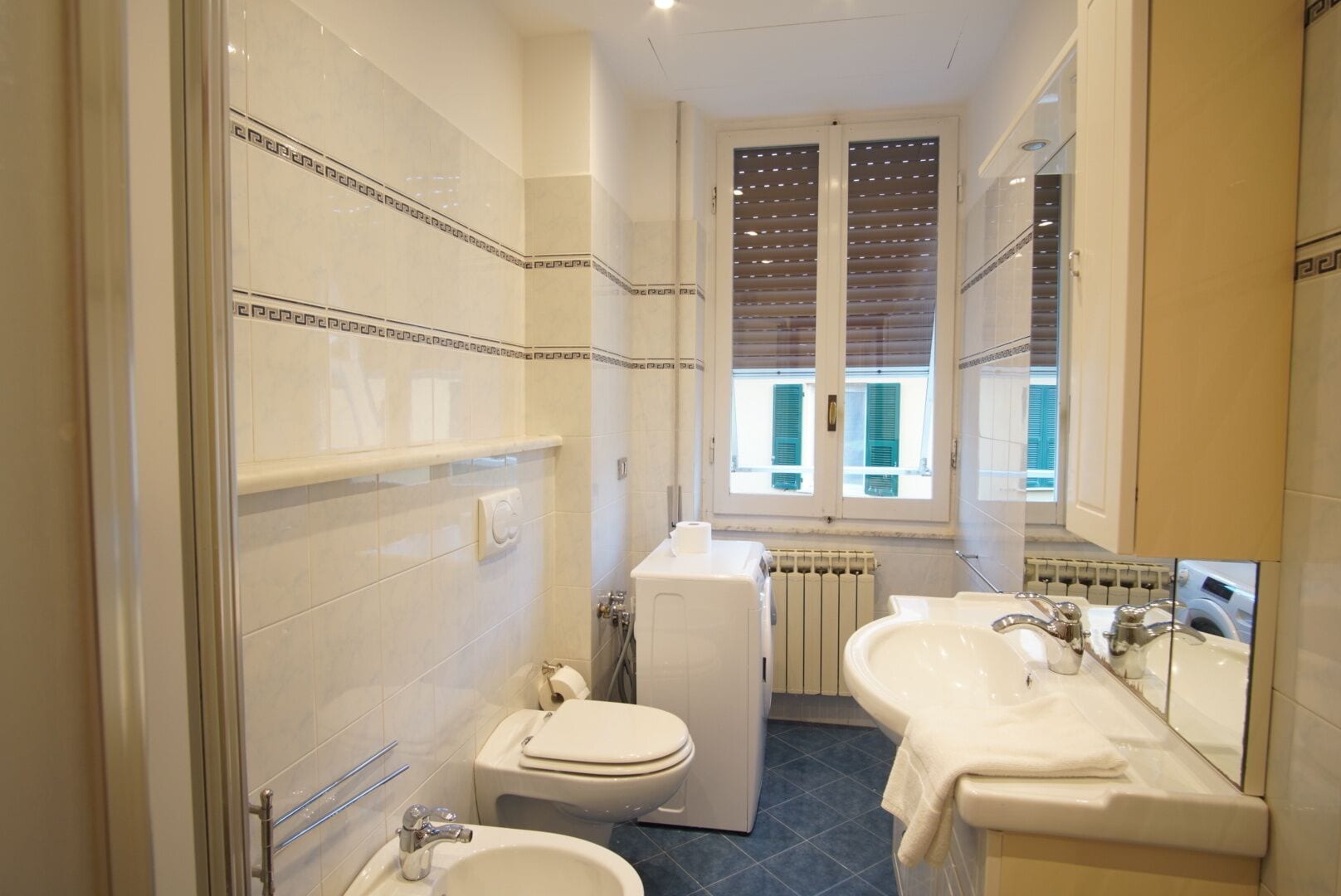 Une petite salle de bain comprenant des toilettes, un bidet, un lavabo et un grand miroir.