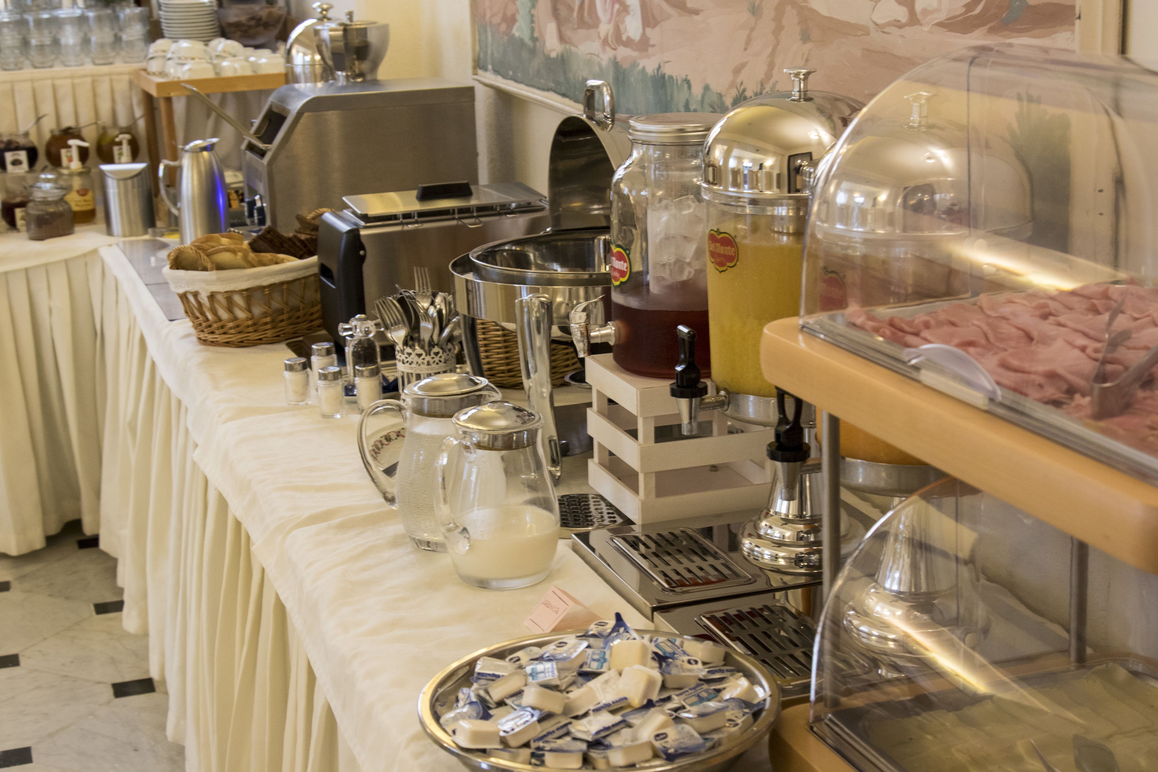 Un buffet avec différents distributeurs de nourriture et de boissons, ainsi que des ustensiles et des récipients.
