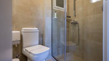 Un baño moderno con ducha de vidrio, inodoro y secador de manos.