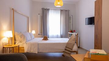 Una habitación de hotel con una cama, mesitas de noche, un televisor y una ventana con cortinas.