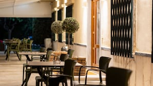 Un espacio exterior para comer con mesas y sillas, un área de estar cubierta y una pared decorativa.