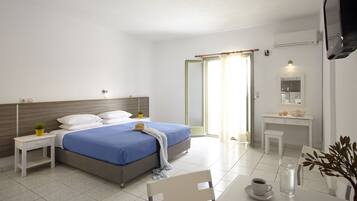 Ein modernes Hotelzimmer mit Bett, Nachttischen, Schreibtisch, Stuhl, Fernseher und einem durch eine geöffnete Tür einsehbarer Badezimmer.