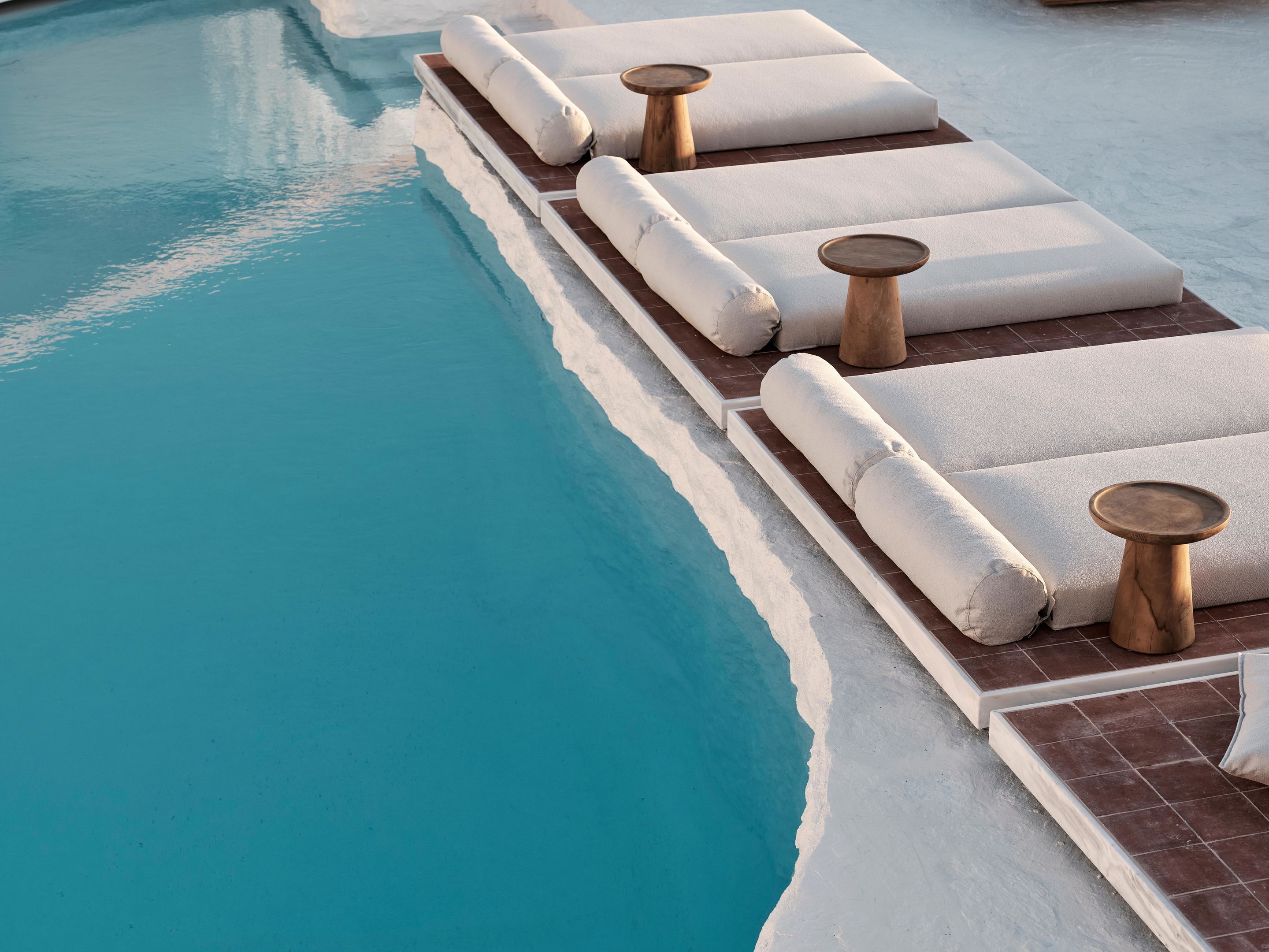 A poolside area with sun loungers and wooden tables.