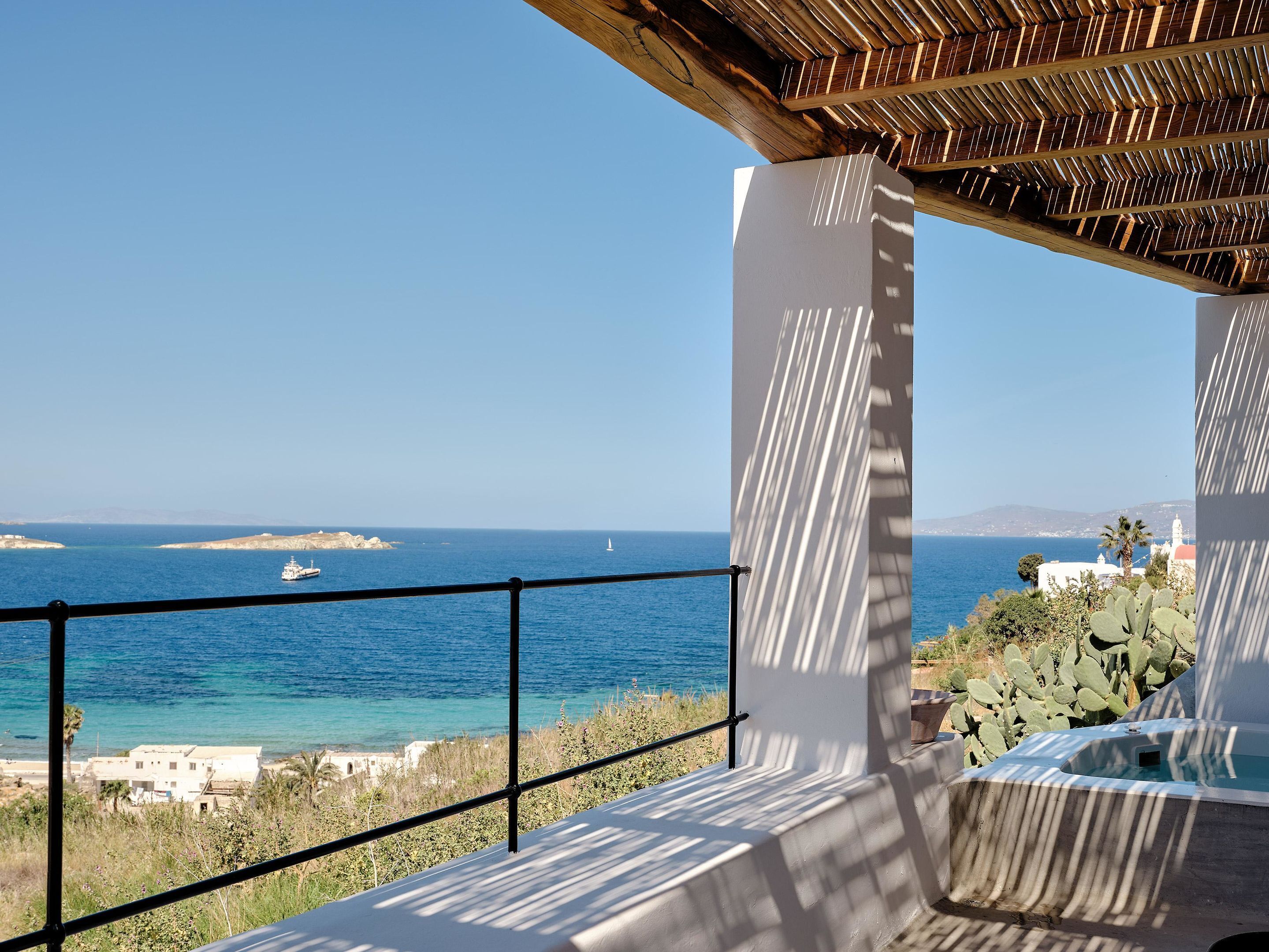 Un balcón con vistas al mar, una pérgola de madera y una planta de cactus.