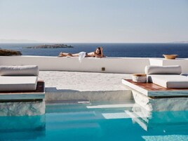Una piscina al aire libre, sombrillas, sillones reclinables de piscina