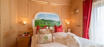 Habitación con paneles de madera, una cama, almohadas, una mesita de noche y un cuadro de un paisaje.