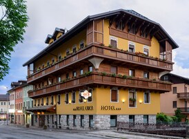 Un hotel de varios pisos con balcones decorados con flores, un letrero que indica que es un hotel y una base de piedra.
