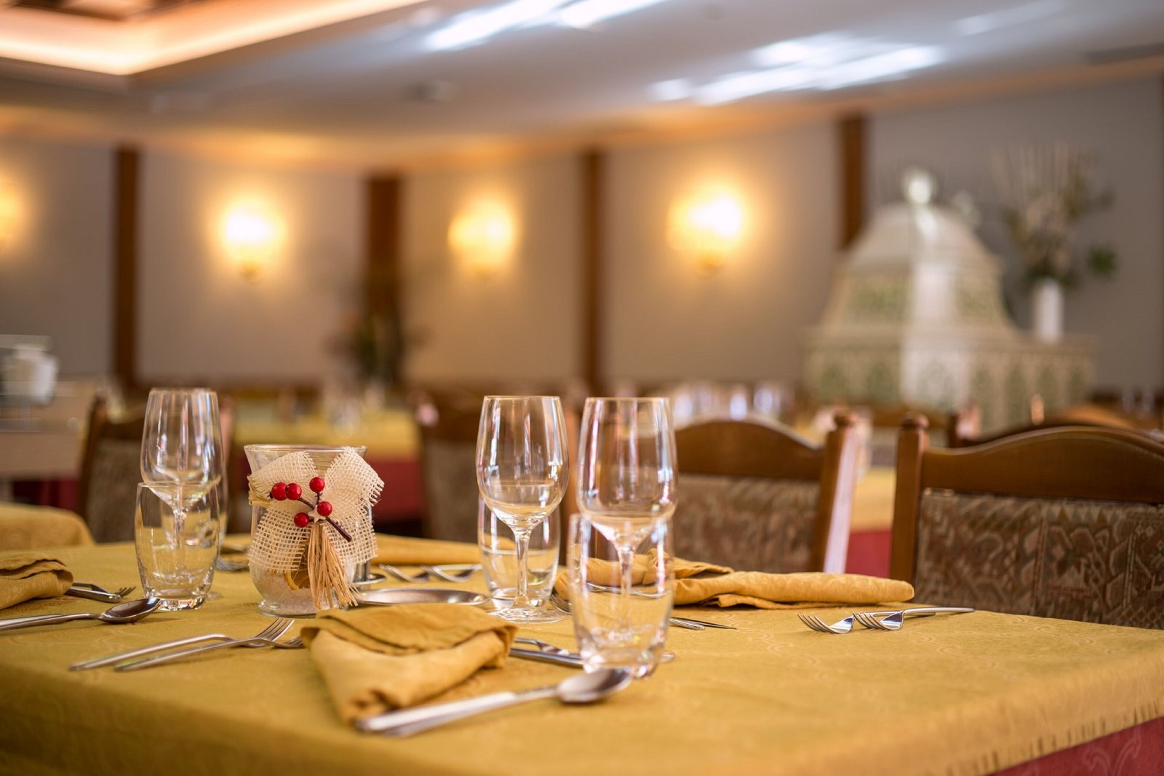 A dining table set with clear glasses, cutlery, and a decorative napkin holder.