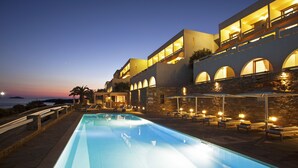 Un hôtel moderne doté d’une piscine, d’un espace extérieur aménagé et offrant une vue sur la mer au crépuscule.