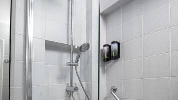 A modern shower with a handheld showerhead, a fixed showerhead, and a handheld shower hose.