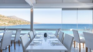 Un coin repas avec une table dressée pour six personnes, offrant une vue sur la côte.