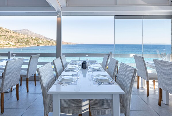 Comedor con una mesa dispuesta para seis personas, con vistas a la costa.