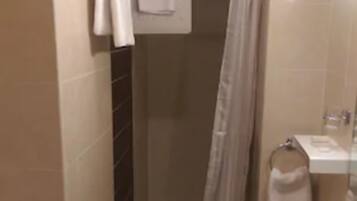 A small bathroom with a toilet, a sink, and a shower.