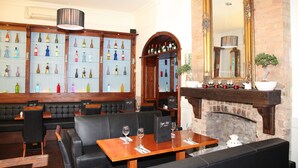 A restaurant with wooden tables and black leather booths, a brick fireplace, and shelves of wine bottles. - Harding Hotel (Dublin)