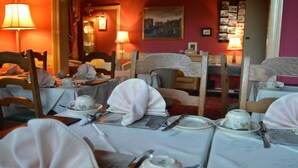 Un comedor con mesas dispuestas para servicio de té, con manteles blancos, tazas y platitos.