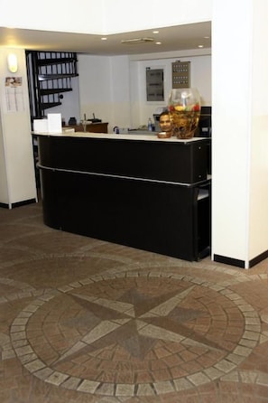 Una reception con un bancone nero, un vaso decorativo e una sveglia a muro.