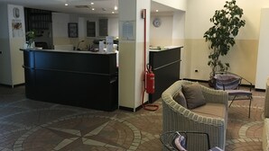 A reception area with a counter, a fire extinguisher, a clock, and a potted plant. - Hotel Nettuno (Milan)