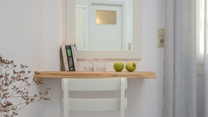 A white chair with a wooden shelf above it, holding two apples and a book. - Soula Naxos (Naxos)