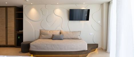 Un dormitorio moderno con cama, televisor montado en la pared y armario de madera.