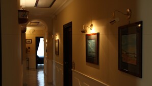 A hotel hallway with framed artwork on the walls, a tiled floor, and a door at the end. - B&B Santa Lucia 50 (Naples)